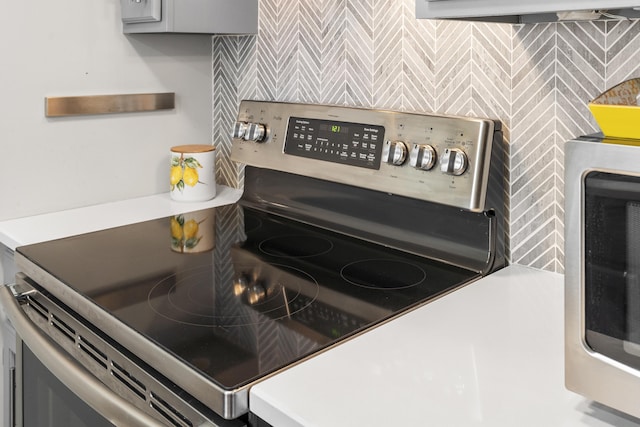 room details with electric range, tasteful backsplash, gray cabinets, and light countertops