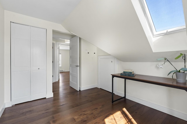 office featuring dark wood-style floors, vaulted ceiling with skylight, and baseboards