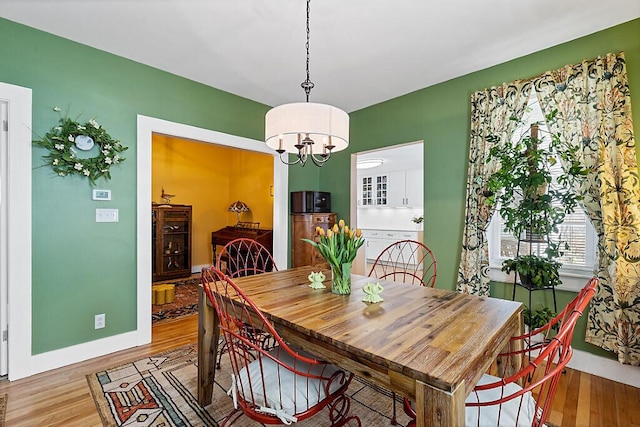 dining room with light wood-type flooring, baseboards, and a chandelier