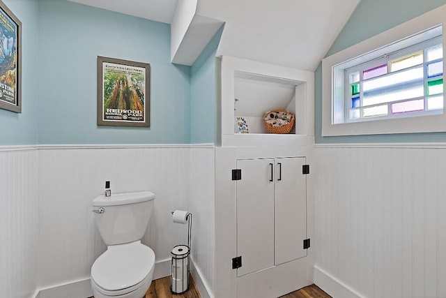 bathroom featuring wainscoting, toilet, lofted ceiling, and wood finished floors