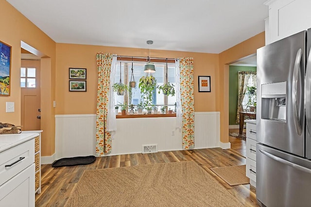 kitchen with visible vents, plenty of natural light, a wainscoted wall, and stainless steel fridge with ice dispenser
