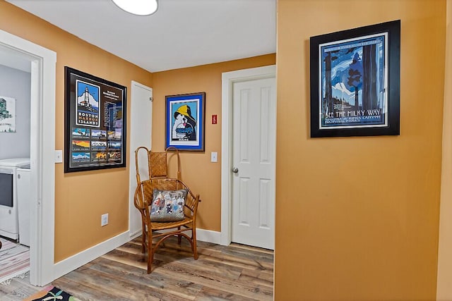 sitting room featuring washing machine and dryer, baseboards, and wood finished floors