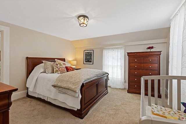 bedroom featuring light colored carpet, baseboards, and vaulted ceiling
