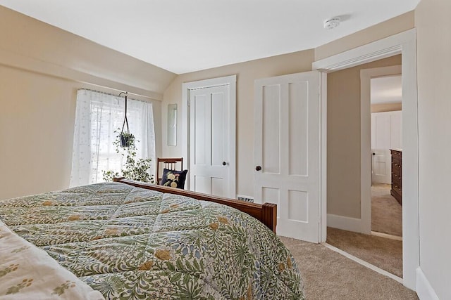 bedroom with a closet, baseboards, carpet, and lofted ceiling