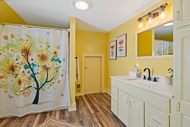 full bathroom featuring curtained shower, vanity, baseboards, and wood finished floors