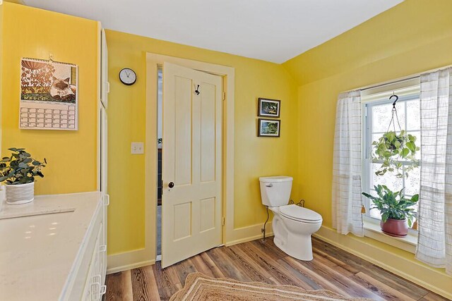 bathroom with toilet, wood finished floors, and baseboards