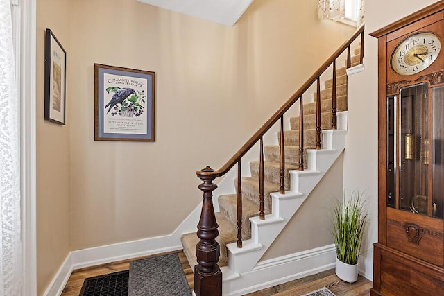 staircase featuring baseboards and wood finished floors