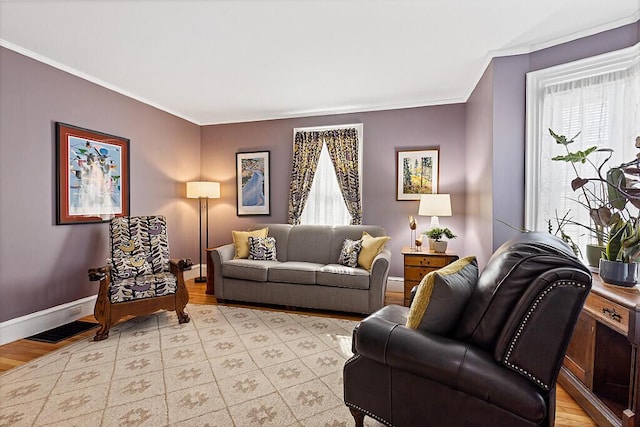 living area with light wood finished floors, visible vents, baseboards, and ornamental molding