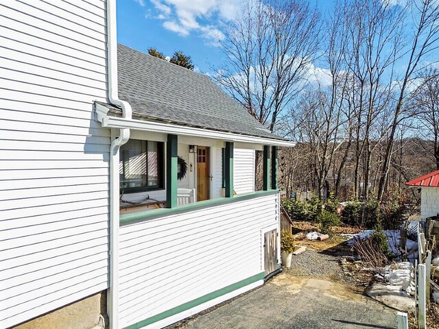 doorway to property featuring roof with shingles