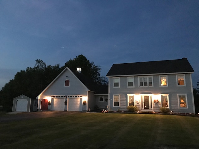 colonial home with a front lawn, an outbuilding, a garage, and driveway