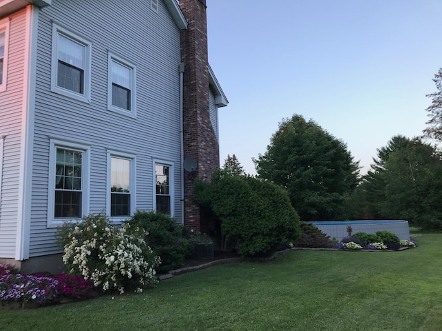 view of side of property featuring a lawn and a chimney