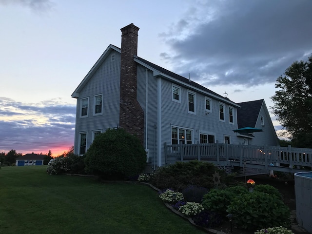 rear view of house with a yard, a chimney, and a wooden deck