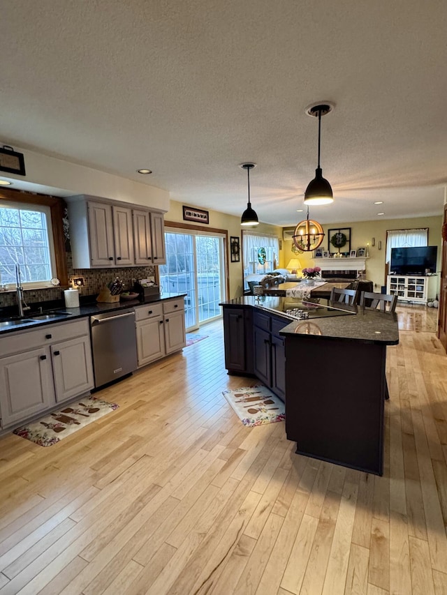 kitchen featuring dark countertops, light wood-style flooring, dishwasher, and a sink