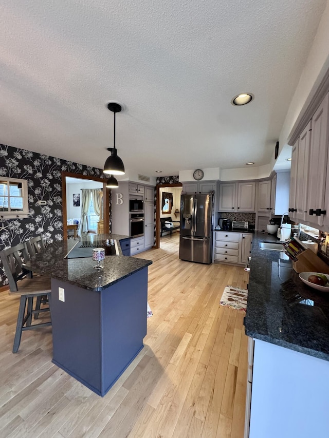 kitchen featuring wallpapered walls, light wood-style flooring, oven, a textured ceiling, and refrigerator with ice dispenser