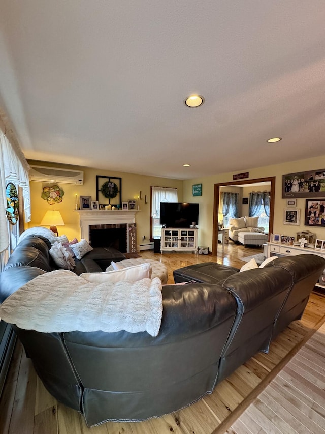 living area with recessed lighting, light wood-type flooring, a fireplace, and a wall mounted AC