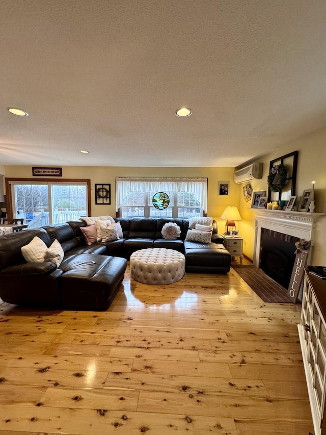 living room with a wall mounted air conditioner, a textured ceiling, recessed lighting, wood-type flooring, and a fireplace