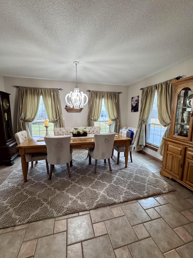 dining area featuring a notable chandelier, a healthy amount of sunlight, and stone tile flooring