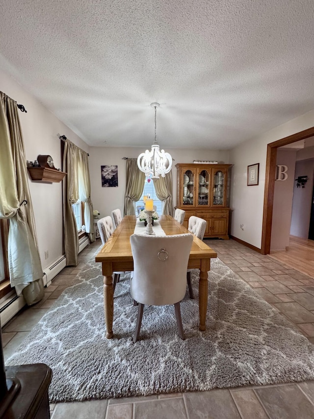 dining area featuring a chandelier, baseboard heating, a textured ceiling, and baseboards