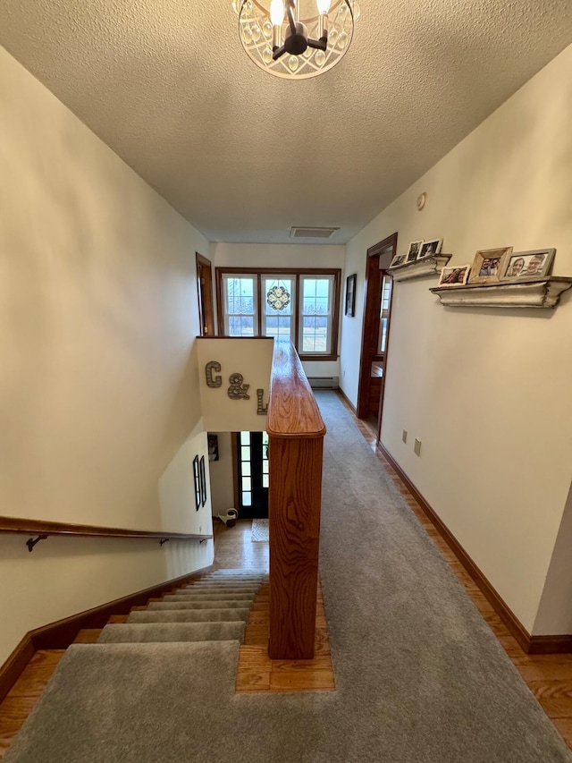 stairs featuring visible vents, baseboards, carpet floors, a notable chandelier, and a textured ceiling