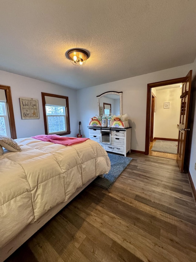 bedroom featuring a textured ceiling, baseboards, and wood finished floors