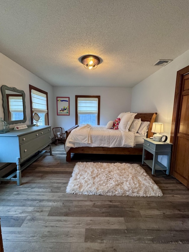 bedroom featuring multiple windows, visible vents, and dark wood-style flooring