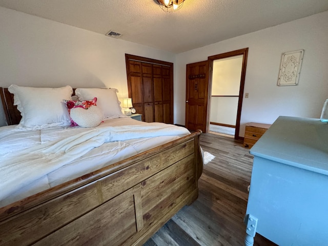 bedroom with wood finished floors, visible vents, and a textured ceiling