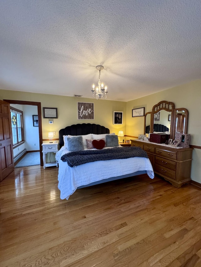 bedroom featuring visible vents, a textured ceiling, an inviting chandelier, and light wood-style flooring