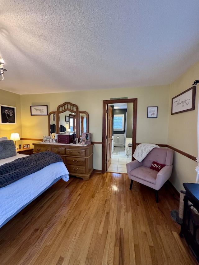 bedroom with a textured ceiling, light wood-type flooring, and baseboards