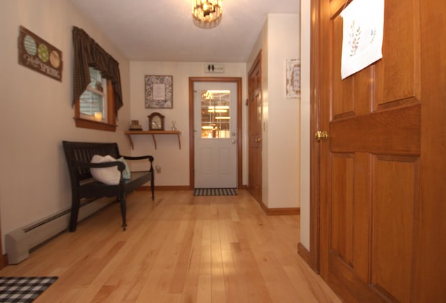 hall with baseboards, light wood-style floors, and a chandelier