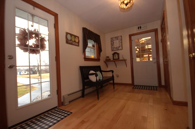 entryway featuring a baseboard radiator, light wood-style flooring, baseboards, and a chandelier