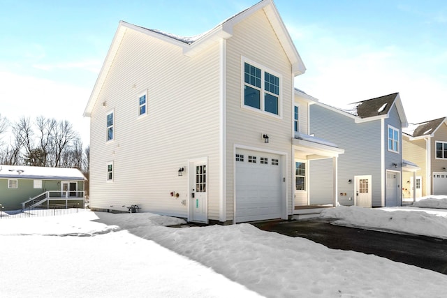 view of snowy exterior featuring an attached garage and driveway