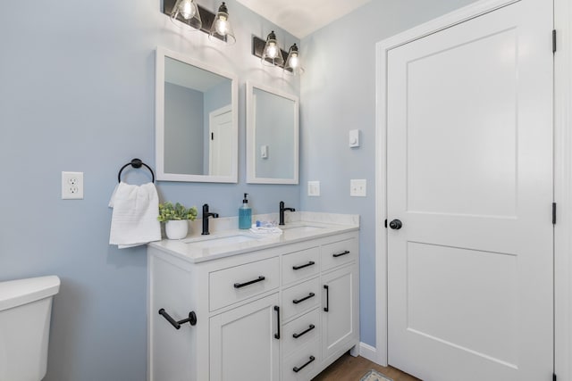 bathroom with a sink, toilet, and double vanity