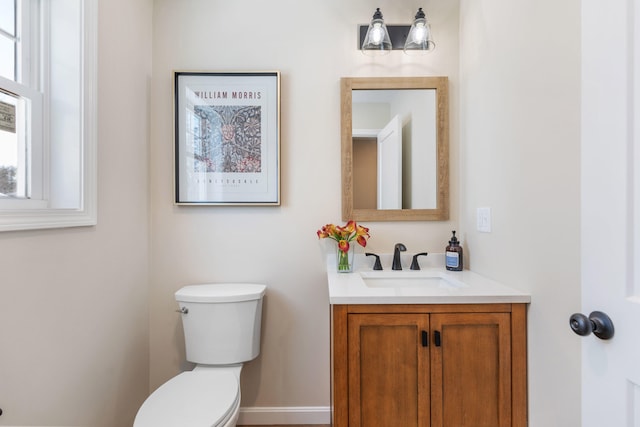 half bath featuring vanity, toilet, and baseboards