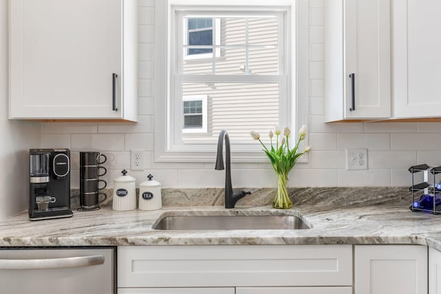 kitchen featuring dishwasher, backsplash, white cabinetry, and a sink