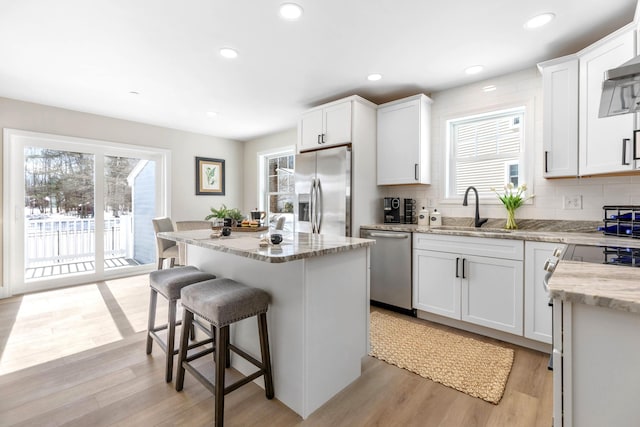 kitchen with plenty of natural light, stainless steel appliances, a kitchen bar, and a sink