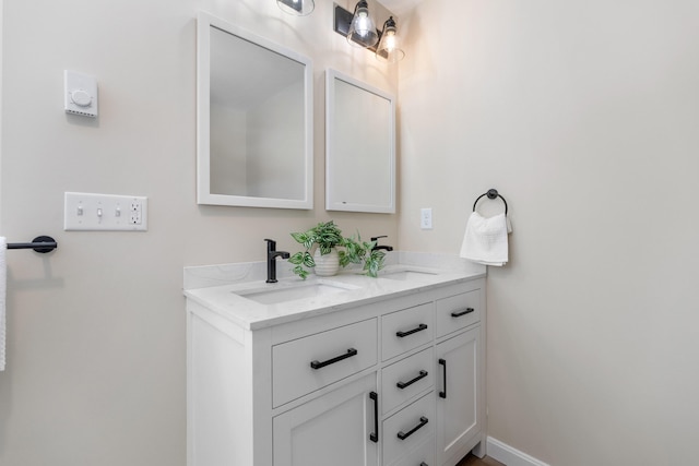 bathroom featuring double vanity, baseboards, and a sink