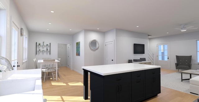 kitchen with dark cabinets, open floor plan, and light wood finished floors