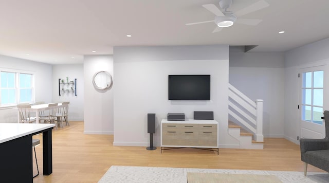 living room with stairs, baseboards, a wealth of natural light, and light wood finished floors