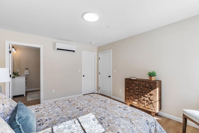 bedroom featuring a wall unit AC, wood finished floors, and baseboards