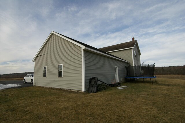 view of home's exterior with a trampoline and a lawn