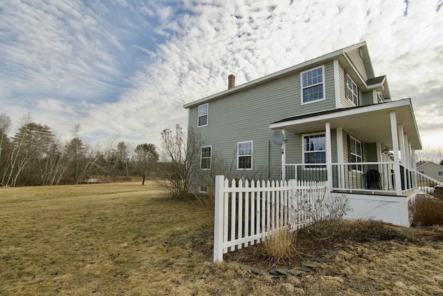 view of home's exterior with covered porch, a yard, and fence