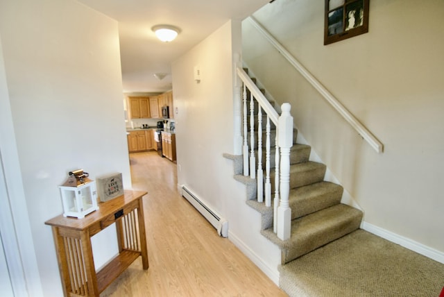 stairway with wood finished floors, baseboards, and baseboard heating