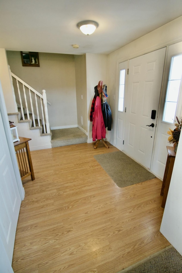 foyer entrance featuring stairway, baseboards, and light wood-style floors