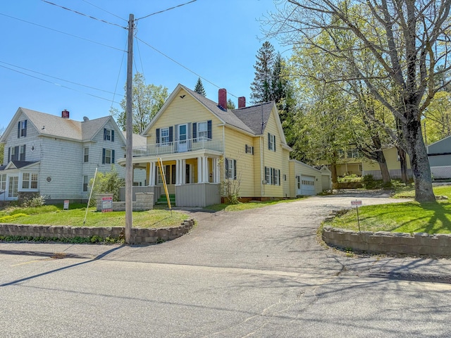 39 Washington St, Rumford, ME 04276 - view of front of house featuring a balcony, a chimney, a garage, dirt driveway, and a front yard