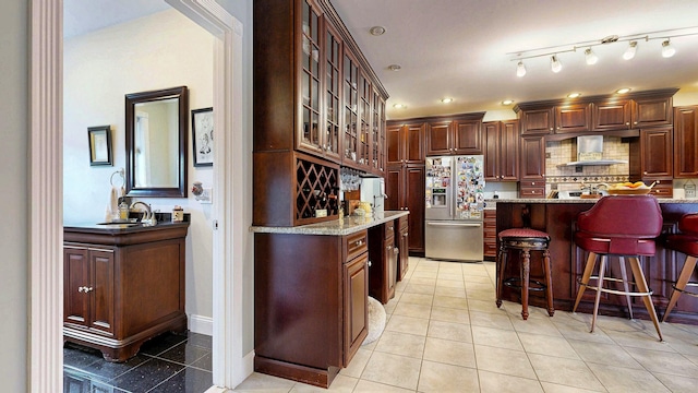 16 Ocean Greens Dr, Saco, ME 04072 - kitchen with wall chimney exhaust hood, glass insert cabinets, stainless steel fridge with ice dispenser, a breakfast bar area, and backsplash