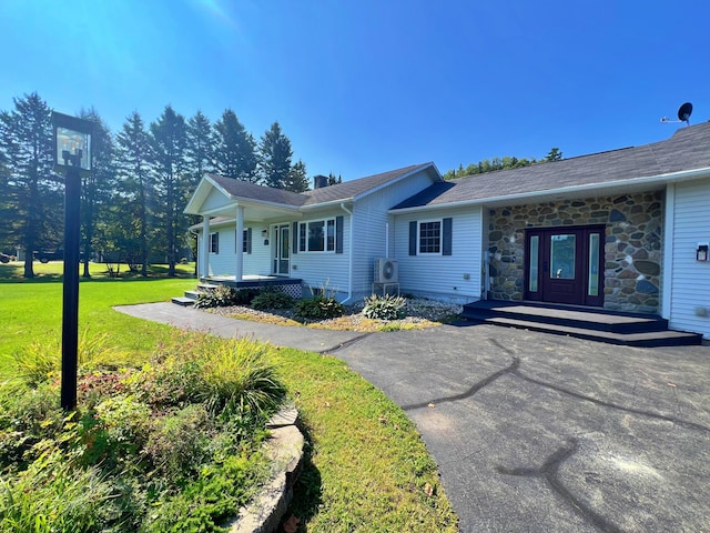 single story home featuring stone siding, covered porch, french doors, and a front yard