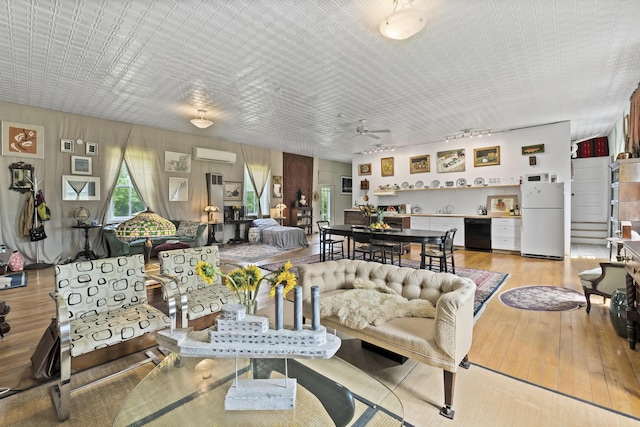 696 Bangor Rd, Troy, ME 04987 - living area with light wood-style floors, an AC wall unit, a ceiling fan, and a healthy amount of sunlight