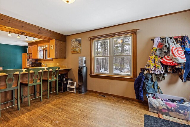 16 Libby Hill Rd, Gardiner, ME 04345 - kitchen with light wood-type flooring, a breakfast bar area, baseboards, and brown cabinetry