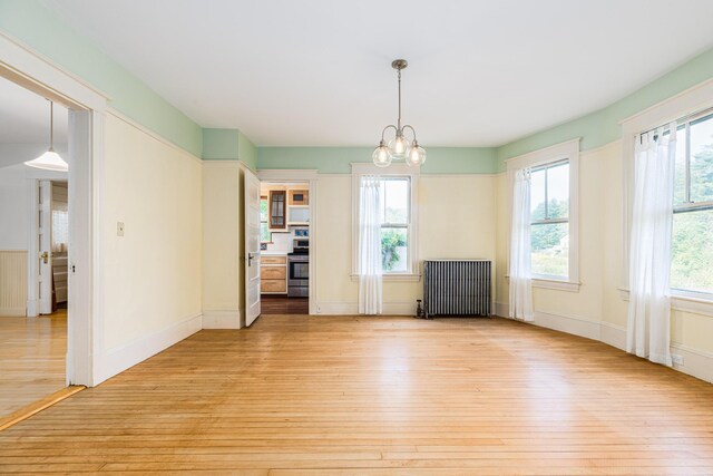 493 Main St, Eliot, ME 03903 - unfurnished dining area featuring radiator, light wood-style floors, plenty of natural light, and a chandelier