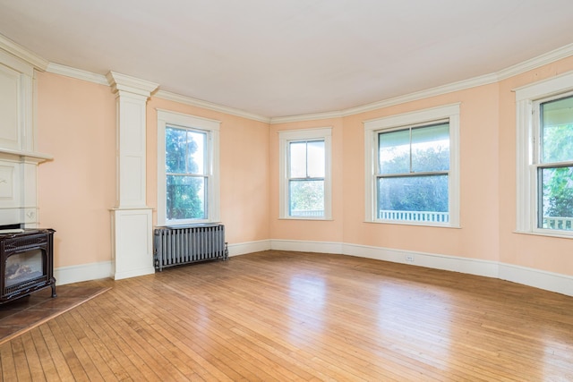 493 Main St, Eliot, ME 03903 - unfurnished living room with radiator, light wood-type flooring, a wood stove, crown molding, and baseboards